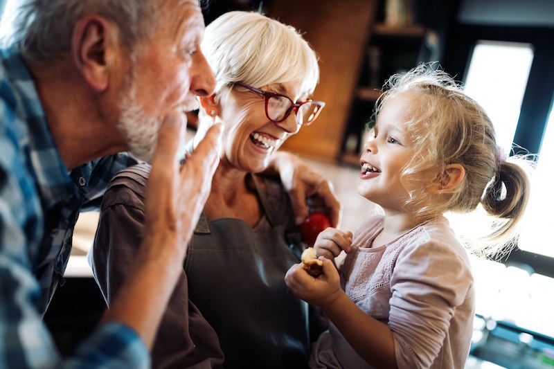 Happy smiling senior grandparents playing with their granddaughter